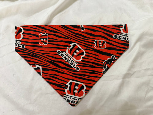 A triangular pet bandana featuring a red and black tiger stripe pattern with Cincinnati Bengals logos, displayed on a white fabric background.